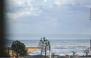 A beach view with a sandy area and a wooden structure, likely a beach chair or umbrella, under a clear sky. - Soldier s Sleep Near Sea (Durrës)