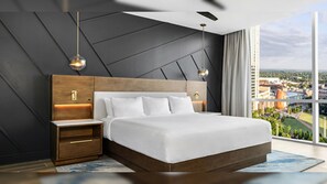 Un dormitorio moderno con una cama grande, cabecero de madera, mesitas de noche e iluminación colgante.