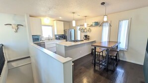 A modern kitchen with a central island, stainless steel appliances, and pendant lighting. - Charming 3-bedroom house CLOSE TO STADIUM - Manhattan (Manhattan)