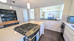 A modern kitchen with a central island, stainless steel appliances, and a view to the dining area. - Charming 3-bedroom house CLOSE TO STADIUM - Manhattan (Manhattan)