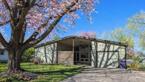 A single-story building with a covered porch, a garage, and a tree with pink blossoms in front. - Charming 3-bedroom house CLOSE TO STADIUM - Manhattan (Manhattan)