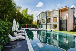 A modern building with a swimming pool, lounge chairs, and umbrellas. - Qingcen Manor (Huzhou)