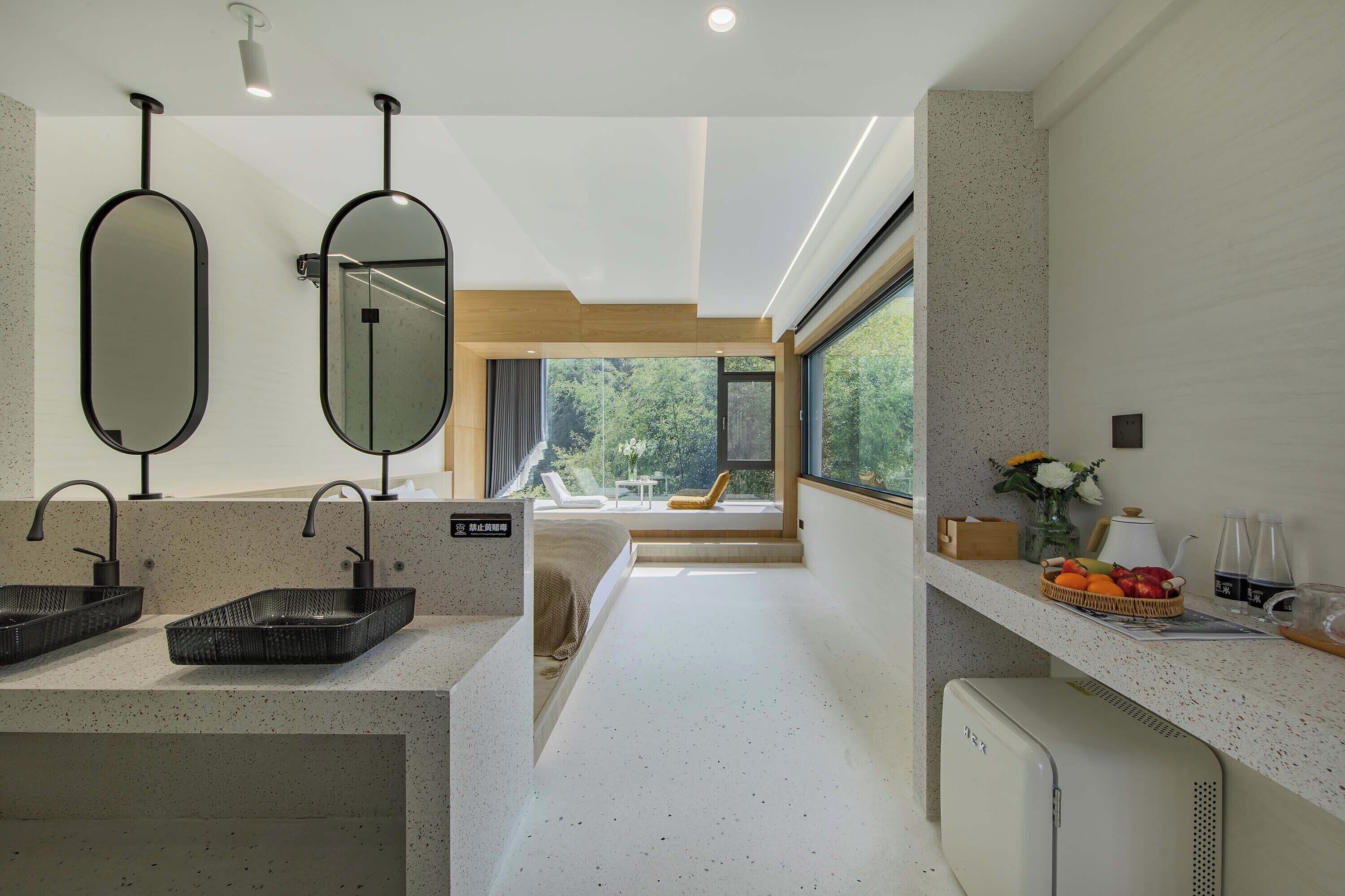 A modern bathroom with two sinks, large mirrors, and a view of a balcony with a chair and flowers.