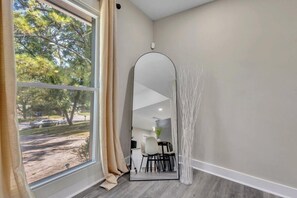 A room with a large window, a mirror, and a view of a parking lot and trees. - Modern 3 Bedroom/3 Bathroom ATL Retreat! (Atlanta)