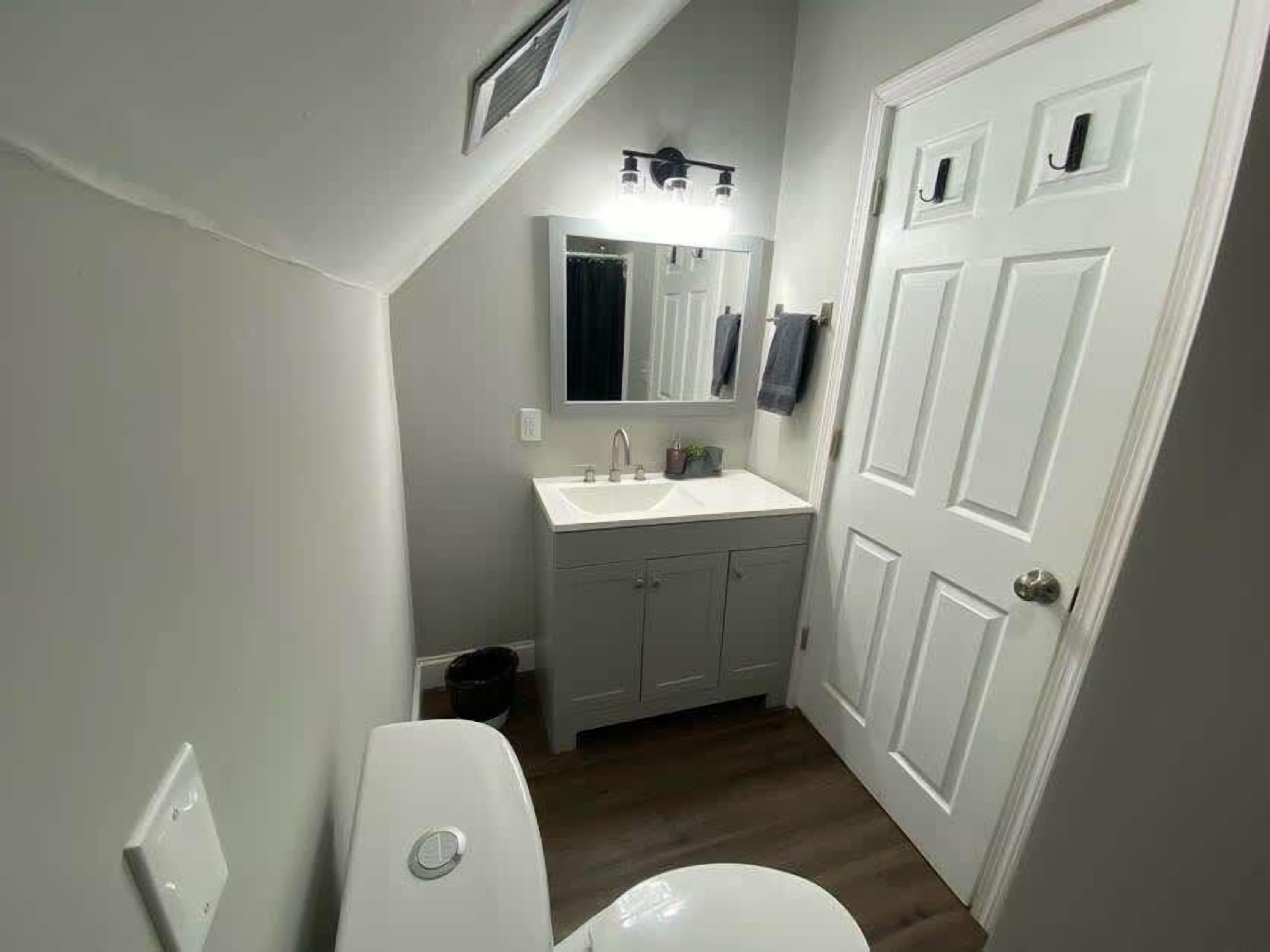 Een badkamer met toilet, wastafel en spiegel.