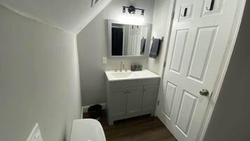 Een badkamer met toilet, wastafel en spiegel.