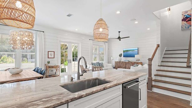A modern kitchen with white cabinetry, a marble countertop, a built-in dishwasher, and a dining area with a table and chairs. - Community pool, 4 Bikes 'Seas the Day' (Santa Rosa Beach)