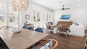 A spacious living area with a wooden dining table, wicker chairs, a white sofa, and a ceiling fan. - Community pool, 4 Bikes 'Seas the Day' (Santa Rosa Beach)