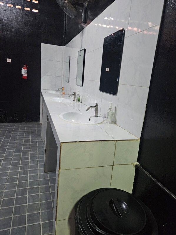 A public restroom with two sinks, a mirror, and a trash bin. - Kai Lions International Capsule Hostel (Pakse)