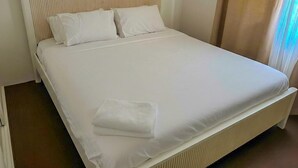 A neatly made bed with white linens and pillows, a wooden headboard, and a white towel on the side. - Sunny Byron Bay House Just 700m from the Beach (Lennox Head)