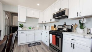 A modern kitchen with white cabinets, a black stove, and a stainless steel microwave. - Cozy Modern 2BR Condo with free Parking (Los Angeles)