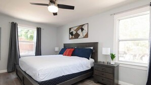 A bedroom with a bed, nightstands, a ceiling fan, and a window with curtains. - Cozy Modern 2BR Condo with free Parking (Los Angeles)