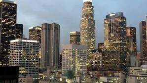 A cityscape with high-rise buildings, some with illuminated windows, and a mix of architectural styles. - Cozy Modern 2BR Condo with free Parking (Los Angeles)
