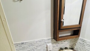 A bathroom with a marble backsplash, a sink with a mirror above it, and a towel rack on the wall.