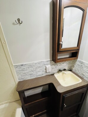 Un baño con salpicadero de mármol, un lavabo con espejo y un perchero en la pared.
