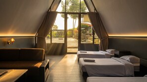 Una habitación con dos camas, un sofá y una mesa. Se ve el exterior a través de amplias ventanas.