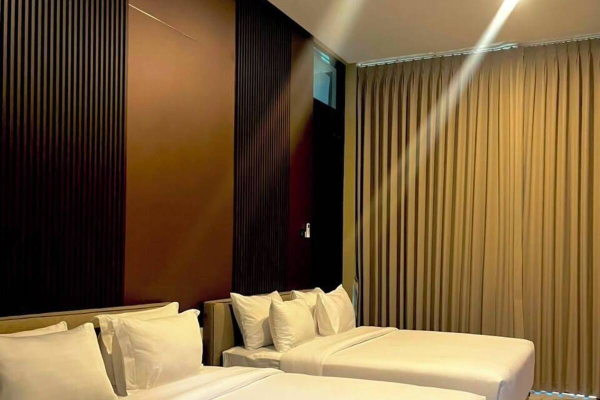 A hotel room with two beds, a large window with curtains, and a marble floor.
