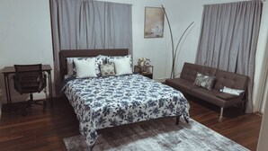 A bedroom with a large bed, a desk, a sofa, and a painting on the wall. - Cozy accommodation very close to everything (Clearwater)