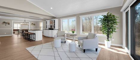 A spacious living area with a kitchen, dining area, and large windows.