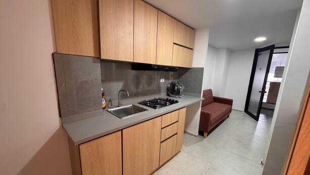 Een moderne keuken met houten kastjes, een roestvrijstalen spoelbak en een gasfornuis.