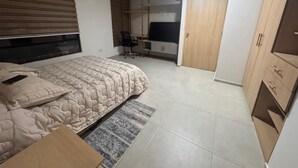 Een slaapkamer met een bed, een bureau, een stoel, een televisie en een kledingkast.