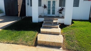 A modern two-story house with a white exterior, a front door, and a set of stone steps leading to the entrance. - Private House with Pool • Ideal for Families and Couples - Fajardo (Fajardo)