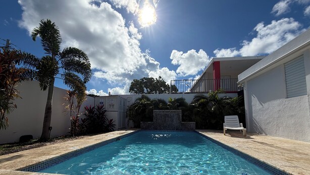 A swimming pool with clear blue water, surrounded by a stone deck and palm trees. - Private House with Pool • Ideal for Families and Couples - Fajardo (Fajardo)