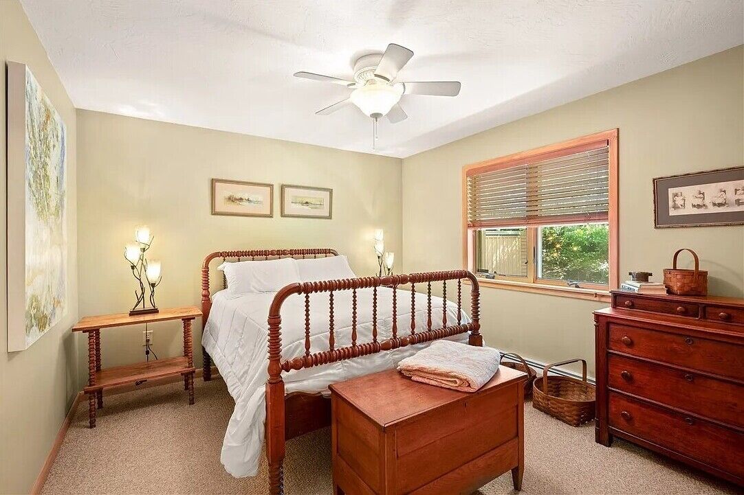 A bedroom with a wooden bed, a nightstand, a dresser, and a ceiling fan.