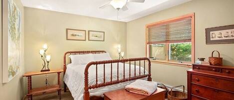 A bedroom with a wooden bed, a nightstand, a dresser, and a ceiling fan.