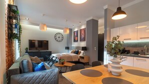Una sala moderna con un sofá, una mesa de comedor con un jarrón, y una zona de cocina con armarios y un lavamanos.