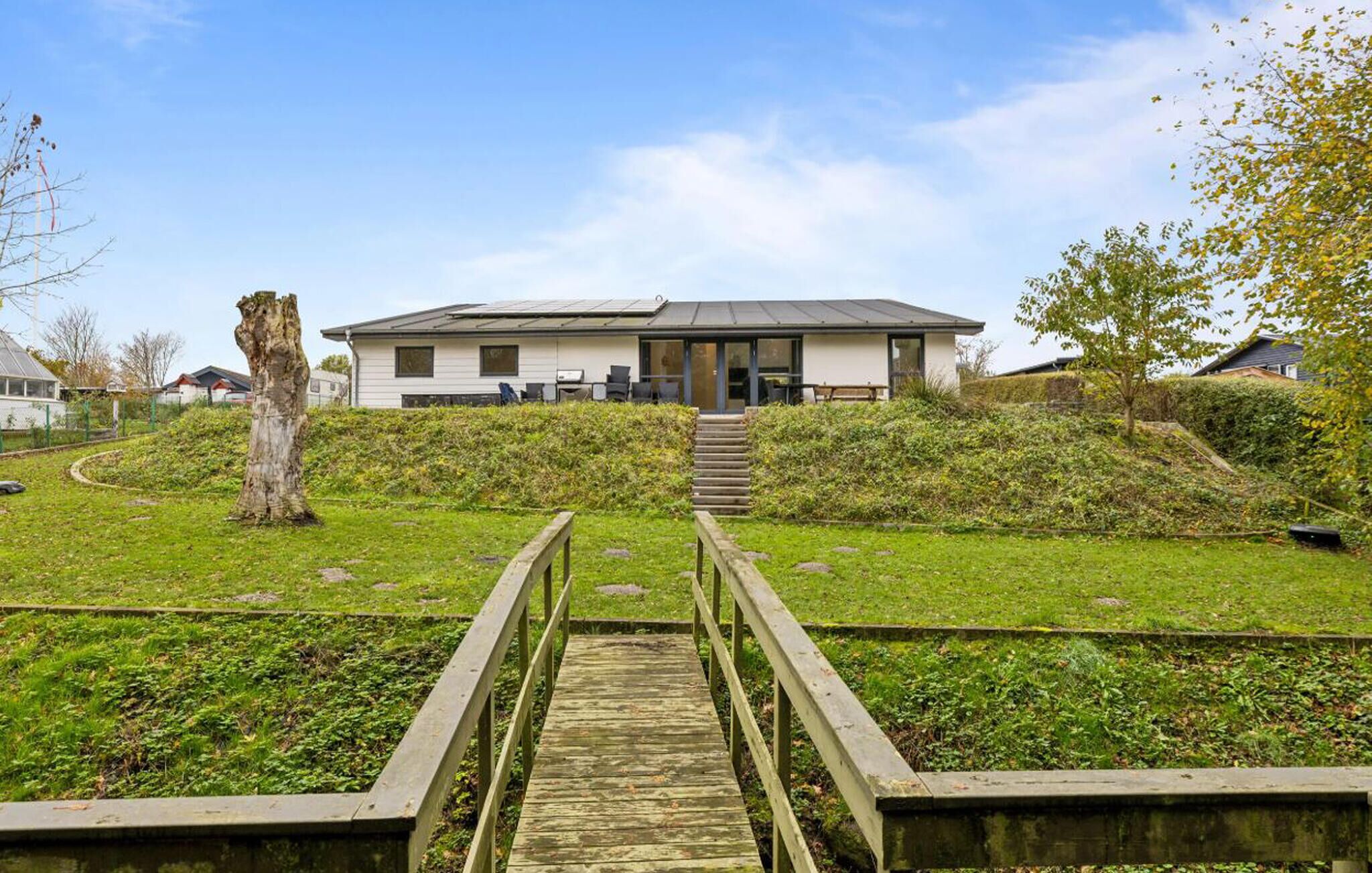 A modern building with a flat roof, a staircase leading to the entrance, and a wooden pathway in the foreground.