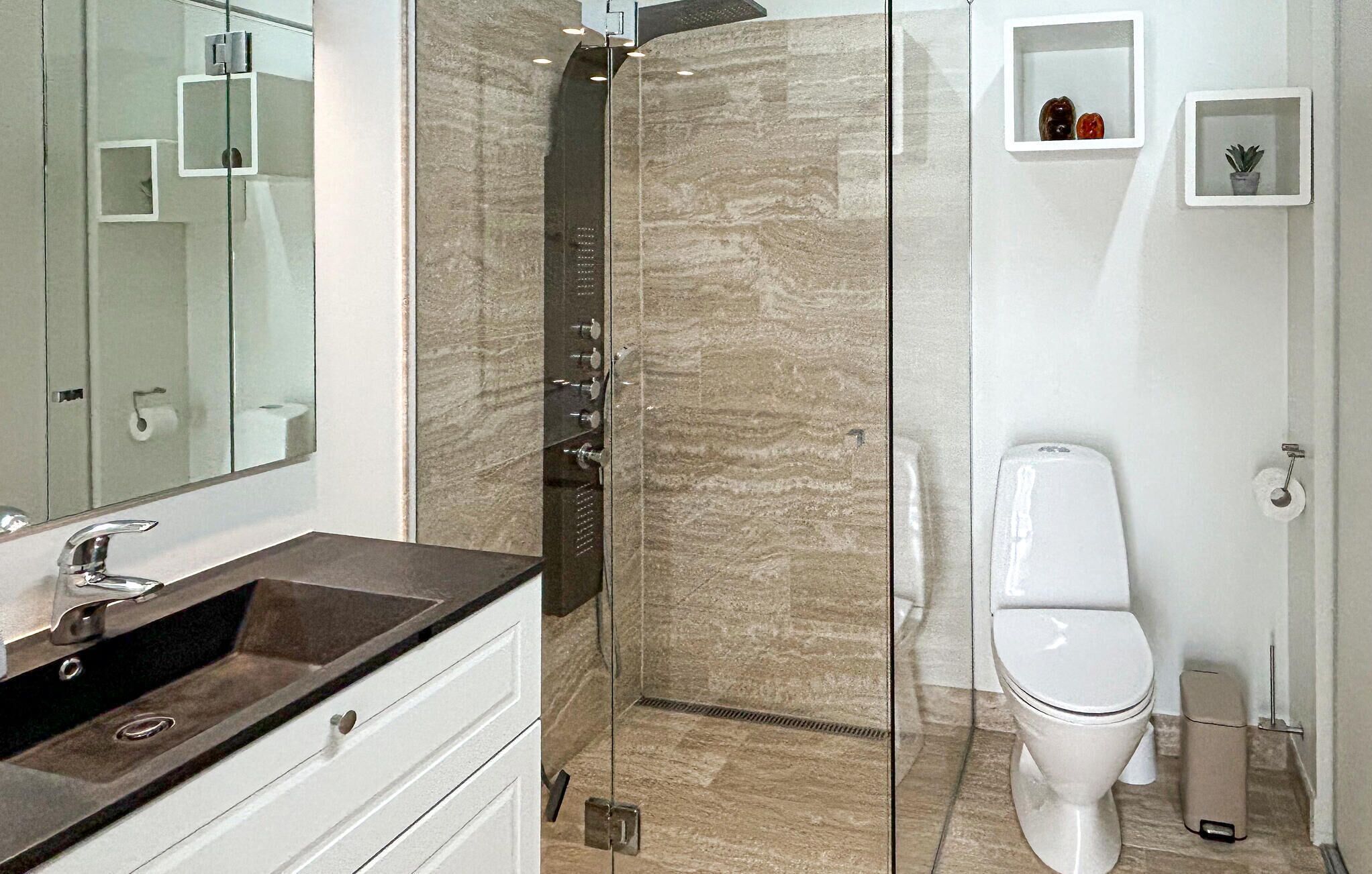 A modern bathroom with a glass-enclosed shower, a white toilet, and a vanity with a sink.