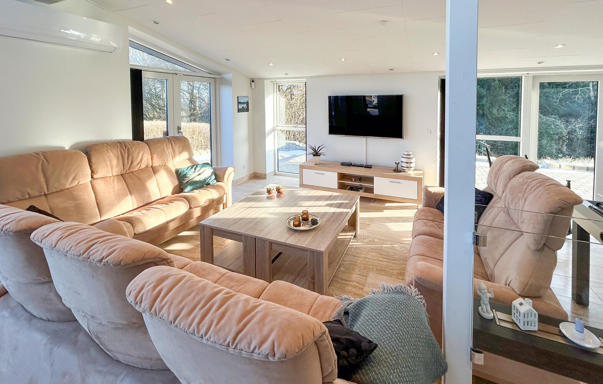 Ein modernes Wohnzimmer mit einer großen Couch, einem Couchtisch und einem an der Wand befestigten Fernseher.