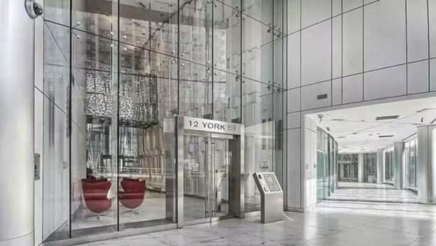 Moderni rakennuksen sisäänkäynti, jossa on kyltti, jossa lukee ”12 YORK ST”, lasiovet ja marmorilattia.