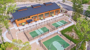 Ein Gebäude mit Basketballplatz, Außenbestuhlung und einem umzäunten Bereich.