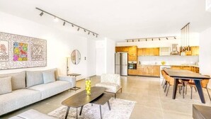 A modern living room with a sofa, coffee table, and dining area.