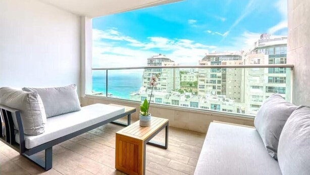 A balcony with a sofa, a small table, and a potted plant.