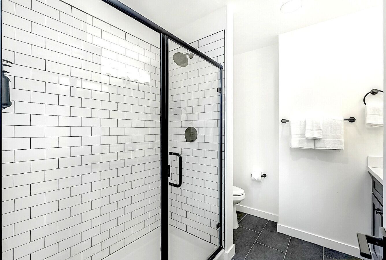 A modern bathroom with white subway tiles, a glass shower enclosure, and a white toilet.