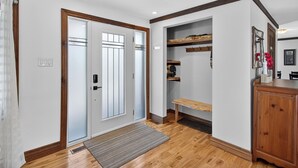 A hallway with a wooden floor, a bench, a cabinet, and a door with frosted glass panels. - Hot Tub Lakeside Cottage – 30 Min from Mont Tremblant (Labelle)
