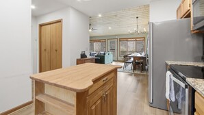 Eine Küche mit Holdekor, einem Edelstahl-Kühlschrank, einer Holzausziehtafel und einem Essbereich mit Tisch und Stühlen.