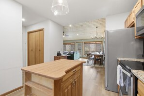 A kitchen with wooden cabinets, a stainless steel refrigerator, a wooden countertop, and a dining area with a table and chairs. - The Beechline~Walk to Slopes~Mtn & Slope Views~Private Club Access~Sleeps 12 (Beech Mountain)