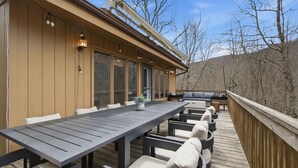 Eine Terrasse mit einem langen Tisch, Stühlen, einem kleinen Topfpflanzen und einer integrierten Sitzbank.