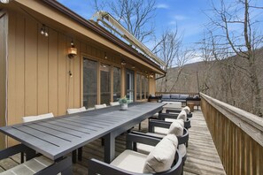 A deck with a long table and chairs, a small potted plant, and a built-in bench area. - The Beechline~Walk to Slopes~Mtn & Slope Views~Private Club Access~Sleeps 12 (Beech Mountain)