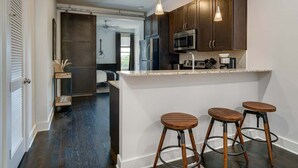 Eine moderne Küche mit dunklen Holzausführungen, Edelstahlgeräten und einer Bar mit Hockern.