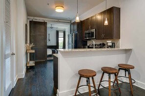 Una cocina moderna con armarios de madera oscura, electrodomésticos de acero inoxidable y una barra con taburetes.