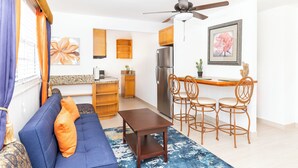 Una sala de estar moderna con un sofá azul, una mesa de comedor de madera y sillas.