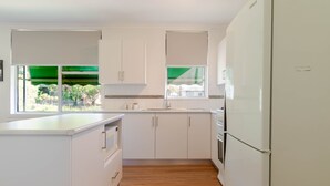 A modern kitchen with white cabinets, a built-in oven, and a refrigerator. - Botanic Base • Pets Welcome • Wagga Wagga (Mount Austin)