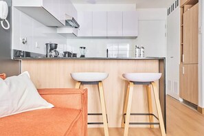 A modern kitchen with white cabinets, a countertop, and two stools. - Geko| Cool 1BR w/ Balcony in Barranco (Barranco)