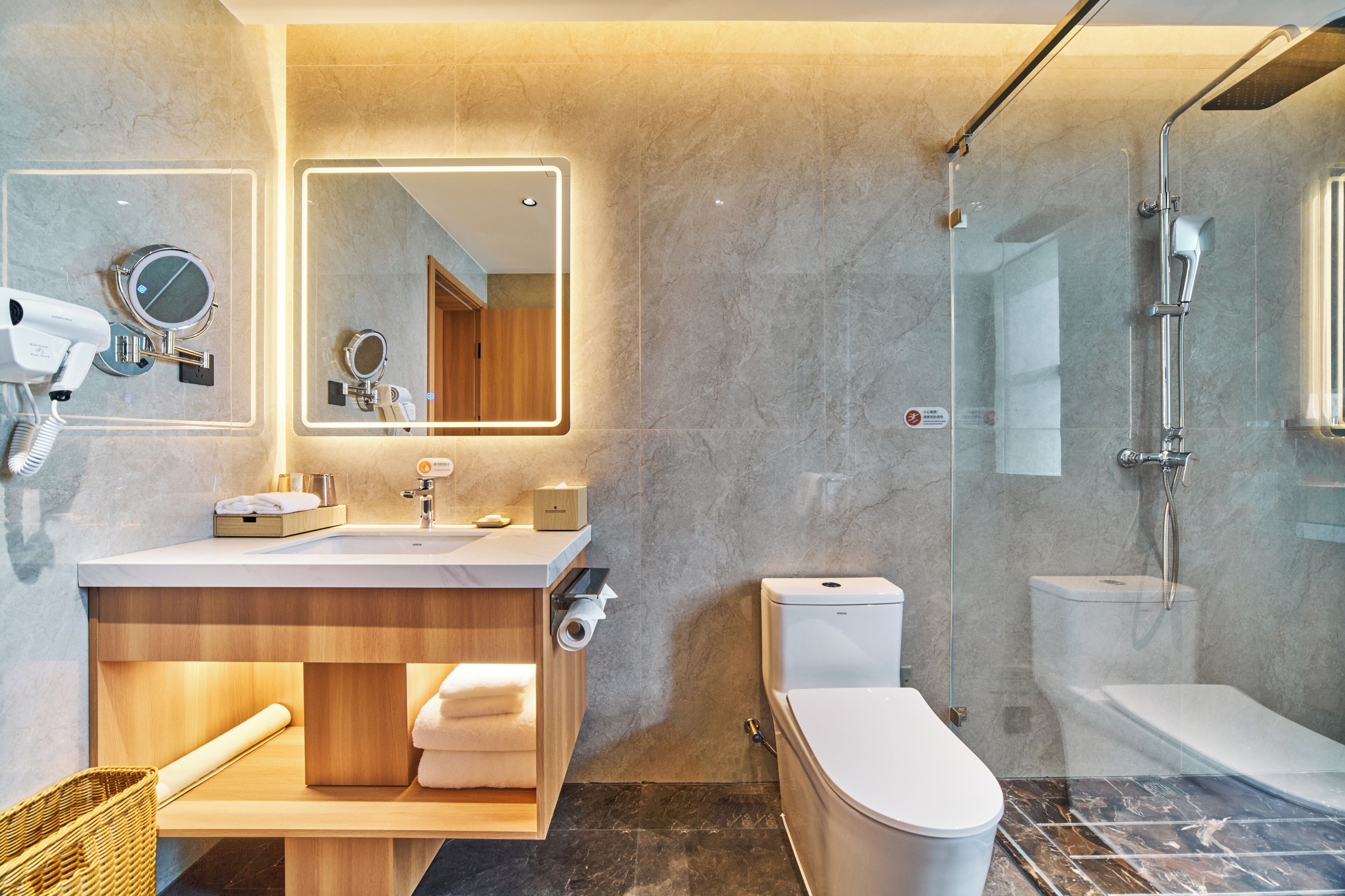 A modern bathroom with a marble sink, a glass-enclosed shower, and a toilet.