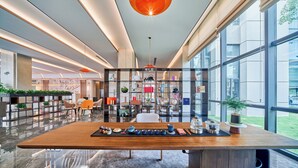 A modern interior with a wooden table displaying kitchenware, a glass partition, and a view of the outside. - Wuhan Tianhe Airport Fliport Garden Hotel (Wuhan)